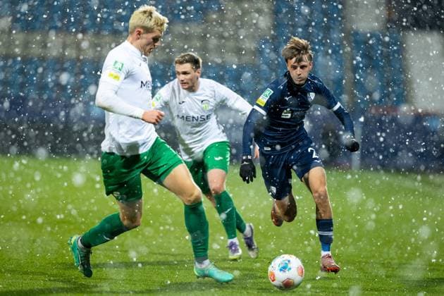 23.11.2025, xkwix, Fußball, Regionalliga West, VfL Bochum 1848 U21, U 21 - FC Gütersloh, Vonovia Ruhrstadion: Luis Frieling (FC Gütersloh 21) im Zweikampf gegen Kacper Koscierski (VfL Bochum U21 2) im Schnee NRW Deutschland