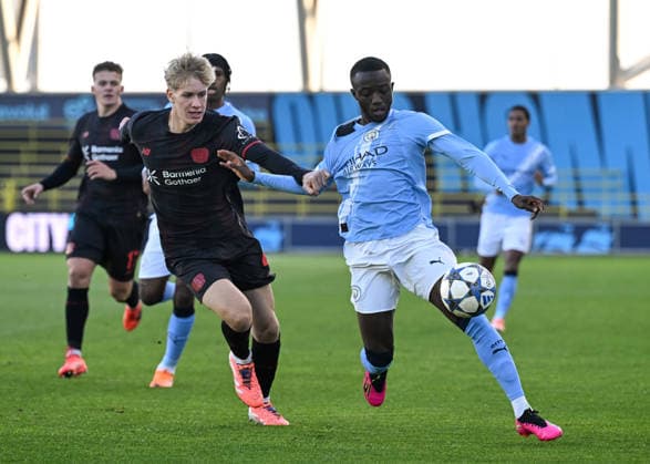 Manchester, England, 25th November 2025. Mahamadou Sangare of Manchester City and Noah Probst of Bayer Leverkusen battle for the ball during the Manchester City U19 vs Bayer Leverkusen U19 UEFA Youth League match at the Academy Stadium, Manchester. Picture credit should read: Cody Froggatt Sportimage EDITORIAL USE ONLY. No use with unauthorised audio, video, data, fixture lists, club league logos or live services. Online in-match use limited to 120 images, no video emulation. No use in betting, games or single club league player publications. SPI_005_CF_MANCHESTER_CITY_U19_V_BAYER_LEVERKUSEN_U19 SPI-4326-0005