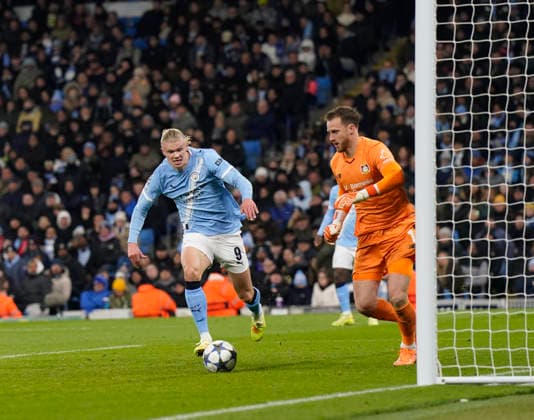 Manchester, England, 25th November 2025. Erling Haaland of Manchester City closes down Mark Flekken of Bayer Leverkusen during the Manchester City vs Bayer Leverkusen UEFA Champions League match at the Etihad Stadium, Manchester. Picture credit should read: Andrew Yates Sportimage EDITORIAL USE ONLY. No use with unauthorised audio, video, data, fixture lists, club league logos or live services. Online in-match use limited to 120 images, no video emulation. No use in betting, games or single club league player publications. SPI_063_AY_Man_City_Leverkusen SPI-4309-0093
