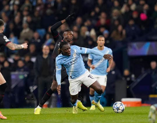 Manchester, England, 25th November 2025. Jeremy Doku of Manchester City fouled by Christian Kofane of Bayer Leverkusen during the Manchester City vs Bayer Leverkusen UEFA Champions League match at the Etihad Stadium, Manchester. Picture credit should read: Andrew Yates Sportimage EDITORIAL USE ONLY. No use with unauthorised audio, video, data, fixture lists, club league logos or live services. Online in-match use limited to 120 images, no video emulation. No use in betting, games or single club league player publications. SPI_066_AY_Man_City_Leverkusen SPI-4309-0096