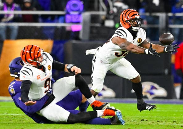 Cincinnati Bengals quarterback Joe Burrow (9) completes a pass to halfback Samaje Perine (34) under pressure from Baltimore Ravens linebacker Kyle van Noy (53) during the second quarter at M&T Bank Stadium in Baltimore, Maryland, on Thursday, November 27 2025.  BAL20251127115 DAVIDxTULIS