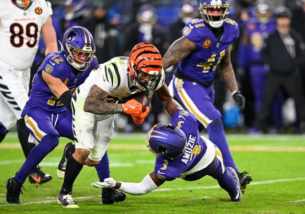 Cincinnati Bengals halfback Chase Brown (C) drives for eight yards before Baltimore Ravens safety Alohi Gilman (12) and Chidobe Awuzie (3) stop him during the fourth quarter at M&T Bank Stadium in Baltimore, Maryland, on Thursday, November 27 2025. Cincinnati won 32-14.  BAL20251127148 DAVIDxTULIS