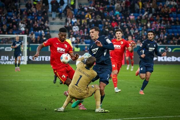 Samuel Essende 9 (FC Augsburg) mit einer Chance, gegen Robin Hranac 2 (TSG 1899 Hoffenheim) und Oliver Baumann 1 (TSG 1899 Hoffenheim), TSG Hoffenheim vs. FC Augsburg, Fussball, Bundesliga, DFL, Saison 2025 2026, Hinrunde, 12. Spieltag, 29.11.2025 DFB regulations prohibit any use of photographs as image sequences and or quasi-video Sinsheim Baden-Wuerttemberg Deutschland