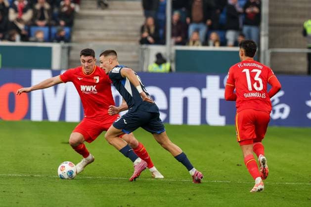 Tim Lemperle 19 (TSG 1899 Hoffenheim) im Duell mit Cedric Zesiger 16 (FC Augsburg), mit Dimitris Giannoulis 13 (FC Augsburg), TSG Hoffenheim vs. FC Augsburg, Fussball, Bundesliga, DFL, Saison 2025 2026, Hinrunde, 12. Spieltag, 29.11.2025 DFB regulations prohibit any use of photographs as image sequences and or quasi-video Sinsheim Baden-Wuerttemberg Deutschland