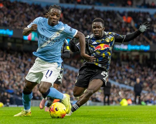 29th November 2025; Etihad Stadium, Manchester, Lancashire, England; Premier League Football, Manchester City versus Leeds United; Jeremy Doku of Manchester City under pressure from Wilfried Gnonto of Leeds United  TimxWilliams