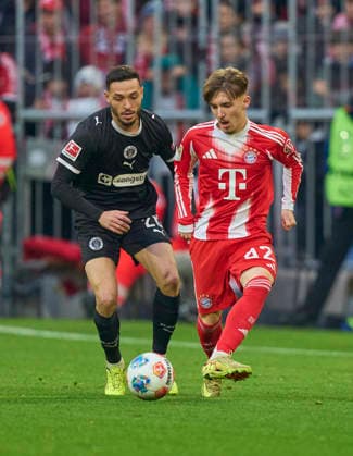 Lennart Karl of FC Bayern München compete for the ball, tackling, duel, header, zweikampf, action, fight against Mathias Pereira Lage of St.Pauli in the match FC BAYERN MÜNCHEN - FC ST. PAULI 3-1 on November 29, 2025 at Allianz Arena München, Germany. Season 2026 2026, 1.Bundesliga, FCB, matchday 12,