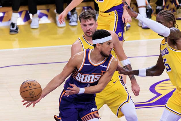 December 1, 2025, Los Angeles, California, USA: Devin Booker 1 of the Phoenix Suns passes the ball as Luka Doncic 77 of the Los Angeles Lakers defends during their regular season NBA, Basketball Herren, USA game on Monday December 1, 2025 at Crypto.com Arena in Los Angeles, California. ARIANA RUIZ PI Los Angeles USA - ZUMAp124 20251201_zaa_p124_002 Copyright: xArianaxRuizx