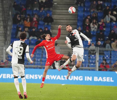 04.12.2025 Basel Schweiz .Fussball Herren Saison 2025 2026 Cup FC Basel - FC Grand-Saconnex. 3:1 Bild : Yannis Sghaier (FC Grand-Saconnex) gegen Adrian Barisic (FC Basel) beim Kopfballduell. (r.) Aktion Zweikampf