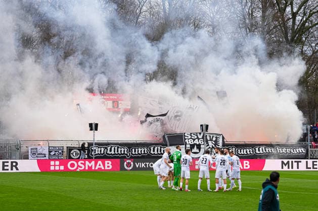 06.12.2025, xydrx, Fußball, 3.Liga, FC Viktoria Köln - SSV Ulm 1846, Saison 2025 2026, Sportpark Höhenberg: Fans vom SSV Ulm 1846 zeigen eine Choreografie mit der Aufschrift: In Ulm um Ulm und um Ulm herum und zünden dabei Pyrotechnik DFB regulations prohibit any use of photographs as image sequences and or quasi-video. Photo: xYannisxDreimannxPressefotoKochx Nordrhein-Westfahlen Deutschland
