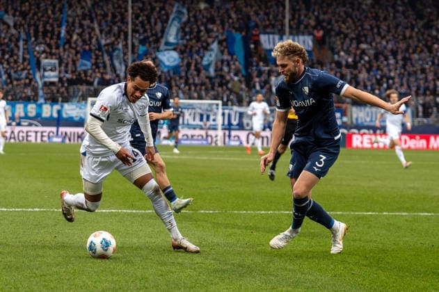 Deutschland, Fussball, 2. Bundesliga, 15.Spieltag 2025 2026: VfL Bochum - Arminia Bielefeld am 06.12. in Bochum (Vonovia-Ruhrstadion): Monju Momuluh (Arminia Bielefeld 14) Philipp Strompf (VfL Bochum 3)