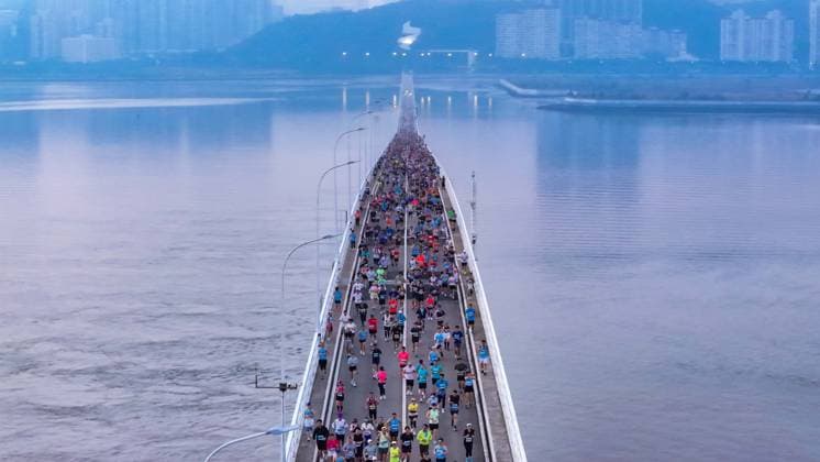 (251207) -- MACAO, Dec. 7, 2025 () -- An aerial drone photo taken on Dec. 7, 2025 shows competitors running through a bridge during the Macao International Marathon 2025 in Macao, South China. () (SP)CHINA-MACAO-MARATHON Xinhua 