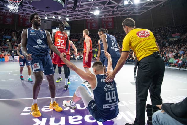 Thomas Khyri (0 MBC) und RJ Gunn (21 MBC) helfen Jure Planinic (44 MBC) auf beim Spiel Bayern München - SYNTAINICS MBC am 07.12.2025 in München. München BMW Park Bayern Deutschland