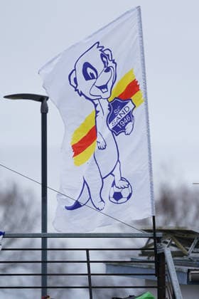 07.12.2025, Fußball, 2. Frauen-Bundesliga, 2025 2026, 12. Spieltag, SC Sand - SG 99 Andernach Maskottchen Sandi mit dem Logo des SC Sand 1946 im Arm und einem Fußball auf einer Fahne.