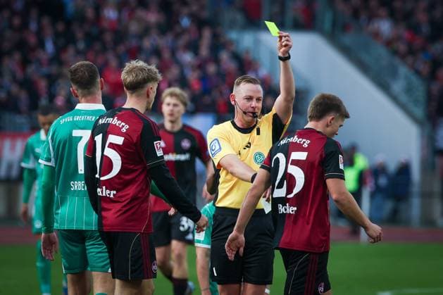 Gelbe Karte fuer Finn Becker 25 (1FC Nuernberg) von Referee Schiedsrichter Lars Erbst nach einem Foulspiel, 1. FC Nuernberg vs. Spvgg Greuther Fuerth, Fussball, 2. Bundesliga, DFL, Saison 2025 2026, Hinrunde, 15. Spieltag, 07.12.2025 DFB regulations prohibit any use of photographs as image sequences and or quasi-video Nuernberg Bayern Deutschland