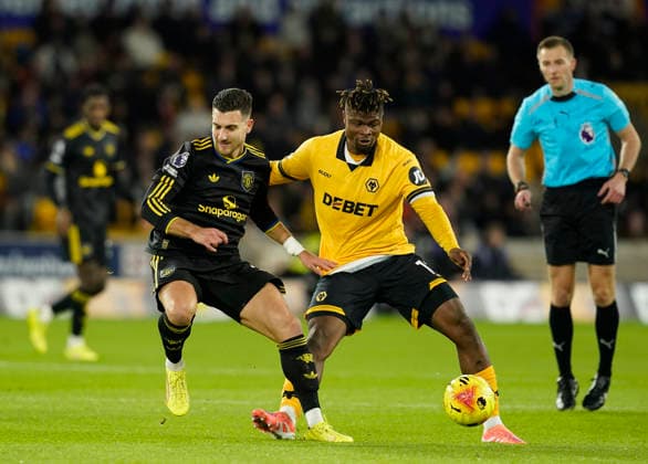 Wolverhampton, England, 8th December 2025. Diogo Dalot of Manchester United, ManU (l) tussles with Emmanuel Agbadou of Wolverhampton Wanderers (r) during the Wolverhampton Wanderers vs Manchester United Premier League match at Molineux, Wolverhampton. Picture credit should read: Andrew Yates Sportimage EDITORIAL USE ONLY. No use with unauthorised audio, video, data, fixture lists, club league logos or live services. Online in-match use limited to 120 images, no video emulation. No use in betting, games or single club league player publications. SPI_040_AY_Wolves_Man_Utd SPI-4356-0040