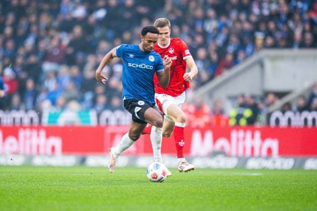 13.12.2025 - Fußball, 2025 2026, 2. Bundesliga, 16. Spieltag, DSC Arminia Bielefeld - 1. FC Kaiserslautern: (L-R) Noah Joel Sarenren Bazee (Bielefeld), Fabian Kunze (Kaiserslautern) DFL REGULATIONS PROHIBIT ANY USE OF PHOTOGRAPHS AS IMAGE SEQUENCES AND OR QUASI-VIDEO.