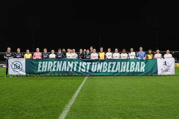 Google Pixel Frauen-Bundesliga, RB Leipzig - TSG Hoffenheim; 14.12.2025 Beide Teams halten auf dem Rasen ein Banner der Aktion: EHRENAMT IST UNBEZAHLBAR. Fußball, Google Pixel Frauen-Bundesliga, Saison 2025 2026, 13. Spieltag: RB Leipzig vs. TSG 1899 Hoffenheim am 14.12.2025, Trainingszentrum Cottaweg, Leipzig. DFB REGULATIONS PROHIBIT ANY USE OF PHOTOGRAPHS AS IMAGE SEQUENCES AND OR QUASI-VIDEO. Copyright: xBEAUTIFULxSPORTS JanxKaeferx