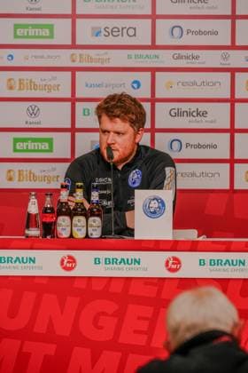 Trainer bei Pressekonferenz am Tisch mit Mikrofon Trainer bei Pressekonferenz Copyright: xMichaelxSchäferx