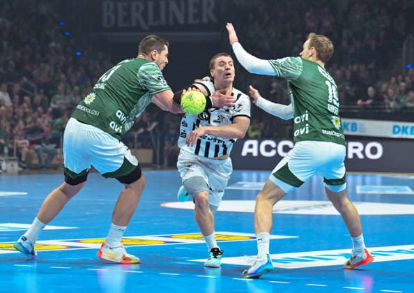 18.12.2025, xlakx, Handball DHB Pokal 1 4 Finale, Fuechse Berlin - THW Kiel v.l. Mijajlo Marsenic (Fuechse Berlin), Elias Ellefsen a Skipagoetu (THW Kiel), Mathias Gidsel (Fuechse Berlin) Zweikampf, Duell, Kampf, tackle Berlin