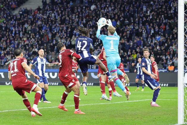 2. Fußball Bundesliga, Hertha BSC - Bielefeld; Torwart Jonas Kersken (Bielefeld, 1) hält, sichert einen Ball vor Deyovaisio Zeefuik (Hertha BSC 42), während der Begegnung in der 2. Fußball Bundesliga, Hertha BSC Berlin - DSC Arminia Bielefeld; 19.12.2025 in Berlin, Olympiastadion. DFB regulations prohibit any use of photographs as image sequences and or quasi video.