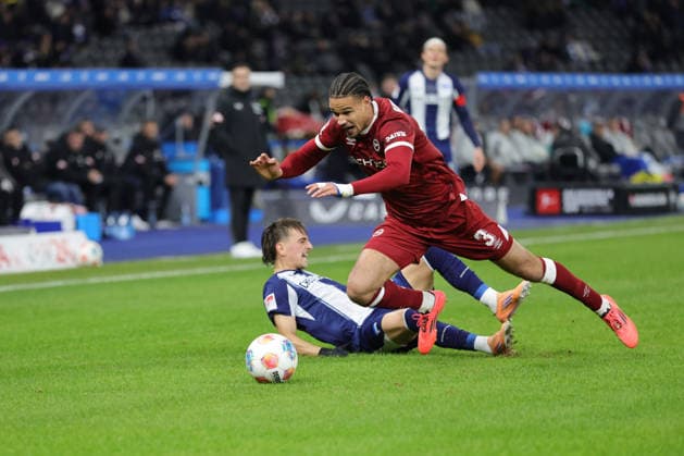 2. Fußball Bundesliga, Hertha BSC - Bielefeld; Micha? Karbownik (Hertha BSC 33) im Zweikampf mit Joel Felix (Bielefeld, 3), während der Begegnung in der 2. Fußball Bundesliga, Hertha BSC Berlin - DSC Arminia Bielefeld; 19.12.2025 in Berlin, Olympiastadion. DFB regulations prohibit any use of photographs as image sequences and or quasi video.