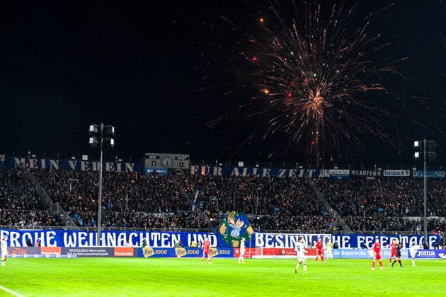 Die Fans des TSV 1860 Muenchen haben in der Westkurve Wunderkerzen angezündet, ein Banner mit Weihnachtswuenschen aufgehaengt und Raketen werden abgeschossen, 20.12.2025, München (Deutschland), Fussball, 3. Liga, TSV 1860 München - SC Verl, DFB DFL REGULATIONS PROHIBIT ANY USE OF PHOTOGRAPHS AS IMAGE SEQUENCES AND OR QUASI-VIDEO.