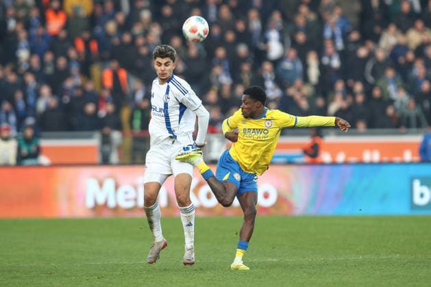 21.12.2025, xtgx, Fussball 2. Bundesliga, Eintracht Braunschweig - FC Schalke 04 v.l. Mertcan Ayhan (Schalke, 43), Christian Conteh (Braunschweig, 32) Zweikampf, Duell, Kampf, tackle verletzt, Verletzung, injury, injured (DFL DFB REGULATIONS PROHIBIT ANY USE OF PHOTOGRAPHS as IMAGE SEQUENCES and or QUASI-VIDEO) Braunschweig