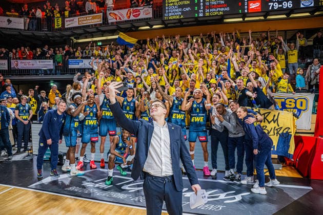 1. Basketball Bundesliga, easyCredit BBL, Saison 2025 2026, Herren, Hauptrunde, 13. Spieltag, 29.12.2025, RASTA Vechta - EWE Baskets Oldenburg Lazar Spasic (Head-Coach - EWE Baskets Oldenburg) beim Siegerselfie mit der Mannschaft und derren Fans Vechta RASTA Dome Niedersachsen Deutschland