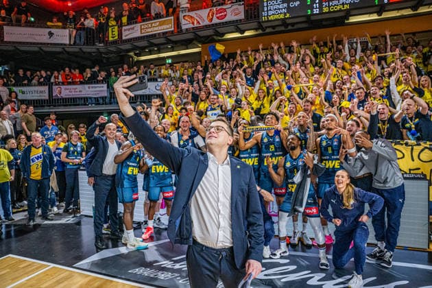 1. Basketball Bundesliga, easyCredit BBL, Saison 2025 2026, Herren, Hauptrunde, 13. Spieltag, 29.12.2025, RASTA Vechta - EWE Baskets Oldenburg Lazar Spasic (Head-Coach - EWE Baskets Oldenburg) beim Siegerselfie mit der Mannschaft und derren Fans Vechta RASTA Dome Niedersachsen Deutschland *** 1 Basketball Bundesliga, easyCredit BBL, Season 2025 2026, Men, Main Round, Matchday 13, 29 12 2025, RASTA Vechta EWE Baskets Oldenburg Lazar Spasic Head Coach EWE Baskets Oldenburg at the victory selfie with the team and their fans Vechta RASTA Dome Lower Saxony Germany