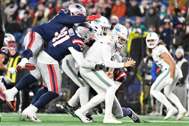 Jan 4, 2026; Foxboro, Massachusetts, USA; Miami Dolphins quarterback Zach Wilson (0) is tackled by the New England Patriots during the second half at Gillette Stadium, in Foxborough, Massachusetts. CSM Foxborough USA - ZUMAc04_ 20260104_faf_c04_036 Copyright: xEricxCanhax