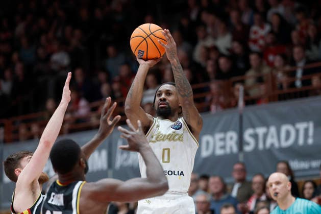 f.l.t.r.: Rickey McGill (Patrioti Levice, 0) with a three against Ryan Schwieger (Fitness First Wuerzburg Baskets, 15) and Eddy Edigin (Fitness First Wuerzburg Baskets, 27), 06.01.2026, Basketball Champions League, Fitness First Wuerzburg Baskets vs. Patrioti Levice, GER, Wuerzburg, Tectake Arena. Copyright: HMBxMedia xHeikoxBecker
