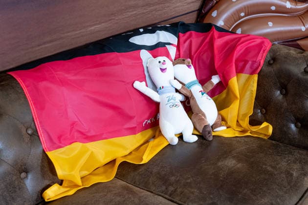 Maskottchen auf einer deutschen Fahne Flagge auf einer Couch in einer Lounge GER, DOSB Olympia-Einkleidung Team Deutschland, Mailand Cortina 2026, 09.01.2026. GER, DOSB Olympia-Einkleidung Team Deutschland, Mailand Cortina 2026, 09.01.2026. Muenchen *** Mascot on a German flag Flag on a couch in a lounge GER, DOSB Olympic Dressing Team Germany, Milan Cortina 2026, 09 01 2026 GER, DOSB Olympic Dressing Team Germany, Milan Cortina 2026, 09 01 2026 Munich Copyright: xEibner-Pressefoto FranzxFeinerx EP_HFR