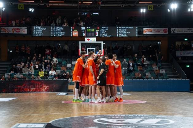 Teamhuddle mit Spielern von Rasta Vechta in orangefarbenen Trikots in der Spielfeldmitte vor dem Spiel am 15. Spieltag der EasyCredit BBL in Vechta. Teamhuddle von Rasta Vechta in orange