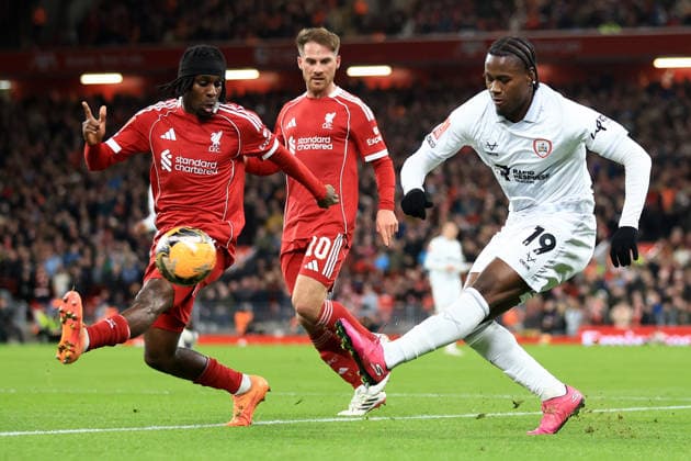Liverpool, England, 12th January 2026. Reyes Cleary of Barnsley has a shot on goal under pressure from Jeremie Frimpong of Liverpool during the Liverpool vs Barnsley FA Cup match at Anfield, Liverpool. Picture credit should read: Jessica Hornby Sportimage EDITORIAL USE ONLY. No use with unauthorised audio, video, data, fixture lists, club league logos or live services. Online in-match use limited to 120 images, no video emulation. No use in betting, games or single club league player publications. SPI_078_JH_Liverpool_Barnsley SPI-4444-0078