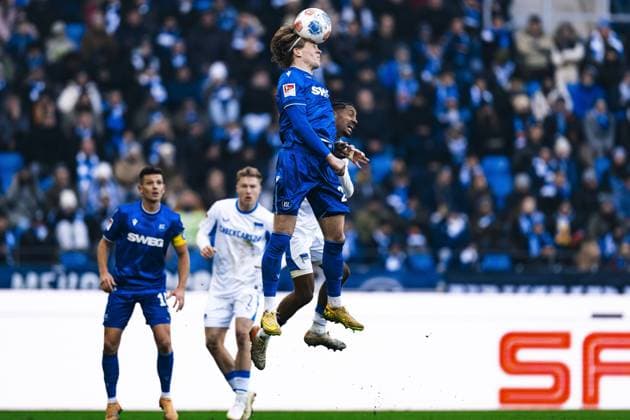 Fabian Schleusener (24; Karlsruher SC) im Luftduell um den Ball gegen einen Spieler von Hertha BSC im Hintergrund, während Marvin Wanitzek (10; Karlsruher SC) aufmerksam beobachtet Luftduell um den Ball