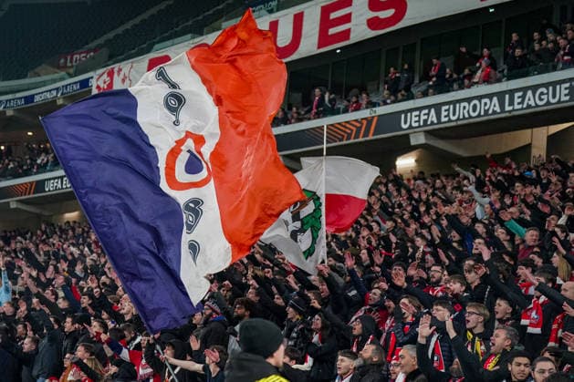 Fussball UEFA Europa League 2025 26, 8. Spieltag OSC Lille vs SC Freiburg Stade Pierre Mauroy (Lille, Frankreich): Heimfans des OSC Lille in der Fankurve, große Vereinsfahnen in Rot-Weiß-Blau geschwenkt, dicht gedrängter Fanblock, kollektiver Jubel und erhobene Arme, lautstarke Unterstützung, emotionale Europapokal-Atmosphäre, UEFA-Europa-League-Branding, Flutlicht, Tribünenblick, Ultras, Fanbewegung, Heimspiel, internationales Fußballereignis, Frankreich, Europa. Copyright: xJOERANxSTEINSIEKx