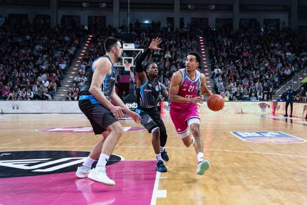 Spielaktion mit Joel Aminu (21; Telekom Baskets Bonn) am Ball, verteidigt von Spielern in schwarzen Trikots in der EasyCredit BBL am 19. Spieltag in Bonn. Joel Aminu (21; Telekom Baskets Bonn) mit Ball in Aktion