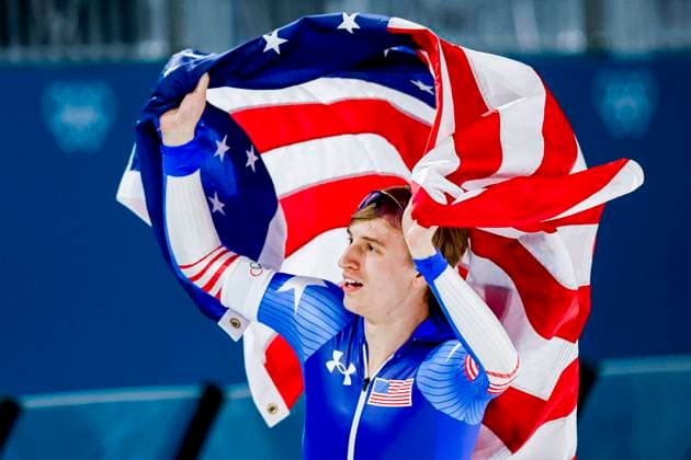 Jordan Stolz of United States of America celebrating and holding flag after Men s 500m, Milano Cortina 2026 Winter Olympics: Day 8, Speed skating, Eisschnelllauf - Milano Cortina 2026 Winter Olympics: Day 8, Milano Speed Skating Stadium, February 14, 2026, Milan, Italy.