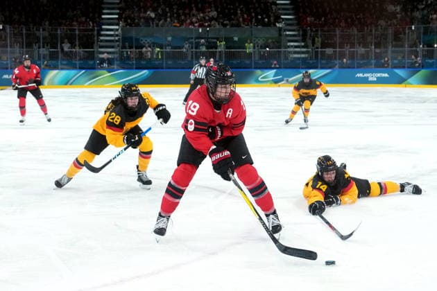 February 14, 2026, Milan, ITALY: Canada s Brianne Jenner (19) passes avoiding the check from Germany s Carina Strobel (14) during the second period of a women s hockey quarterfinal game at the 2026 Winter Olympics, in Milan, Saturday, Feb. 14, 2026. Germany s Katarina Jobst-Smith (28) looks on. Canada News - February 14, 2026  - ZUMAc35_ 20260214_zaf_c35_030 Copyright: xDarrylxDyckx