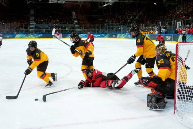 February 14, 2026, Milan, ITALY: Germany s Svenja Voigt (9) gets the puck away from the net as Canada s Laura Stacey (7) falls in front of Germany goalie Sandra Abstreiter (35) during the second period of a women s hockey quarterfinal game at the 2026 Winter Olympics, in Milan, Saturday, Feb. 14, 2026. Canada News - February 14, 2026  - ZUMAc35_ 20260214_zaf_c35_039 Copyright: xDarrylxDyckx
