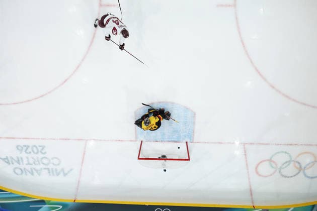 (260215) -- MILAN, Feb. 15, 2026 -- Eduards Tralmaks (top) of Latvia scores during the Ice hockey, Eishockey men s preliminary round group C match between Germany and Latvia of the Milan-Cortina 2026 Olympic Winter games, Winterspiele,Spiele, Summer games in Milan, Italy, Feb. 14, 2026. ) (MICO2026)ITALY-MILAN-OLYMPIC WINTER GAMES-ICE HOCKEY-MEN-PRELIMINARY-GER VS LAT SunxFei 