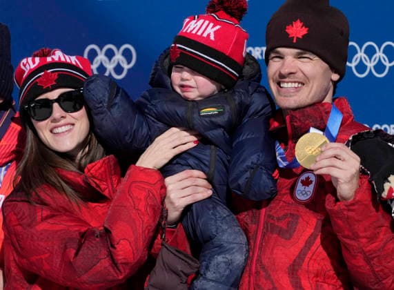 Gold medalist Mikael Kingsbury of Canada poses with his partner Laurence Mongeon and their infant son Henrik after the Men s Freestyle Skiing Dual Moguls competition at the Milano Cortina 2026 Winter Olympic Games, Olympische Spiele, Olympia, OS in Livigno, Italy, on Sunday, February 15, 2026. Ikuma Horishima of Japan won the silver medal and Matt Graham of Australia won the bronze medal.  OLY20260215806 BOBxSTRONG