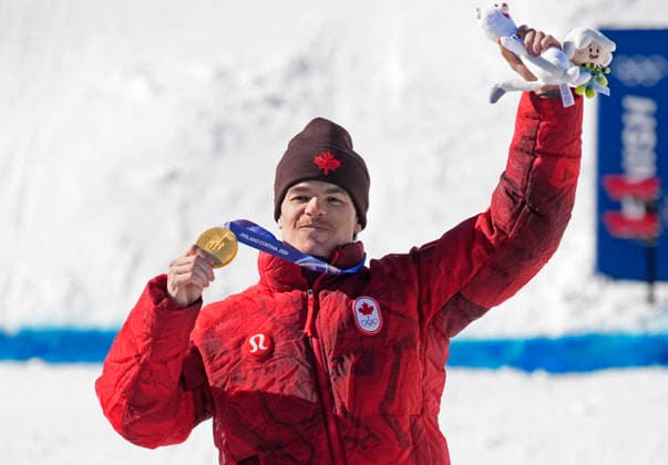 Gold medalist Mikael Kingsbury of Canada poses with his medal after the Men s Freestyle Skiing Dual Moguls competition at the Milano Cortina 2026 Winter Olympic Games, Olympische Spiele, Olympia, OS in Livigno, Italy, on Sunday, February 15, 2026. Ikuma Horishima of Japan won the silver medal and Matt Graham of Australia won the bronze medal.  OLY20260215808 BOBxSTRONG