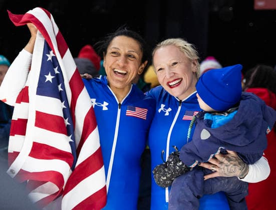 February 16, 2026, Cortina D ampezzo, Lombardy, Italy: Golf medal winner Elana Meyers Taylor of the USA, left, with teammate and bronze medal winner Kaillie Armbruster Humphries after the Women s Monobob at the Cortina Sliding Centre for the Milano Cortina 2026 Winter Olympics. Armbruster Humphries is holding her son Aulden. Cortina Sliding Centre - Monnobob  - ZUMAsc5_ 20260216_oly_sc5_004 Copyright: xErichxSchlegelx