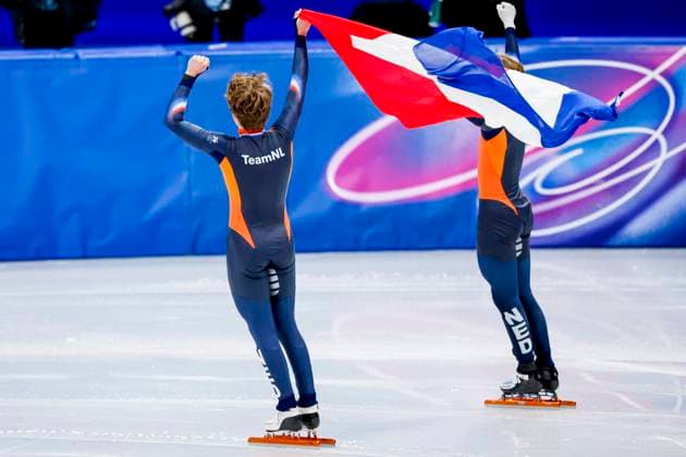 third Jens van t Wout of the Netherlands and second Melle van t Wout of the Netherlands celebrating and holding flag after Men s 500m Finals, Milano Cortina 2026 Winter Olympics: Day 12, Short Track Speed skating, Eisschnelllauf - Milano Cortina 2026 Winter Olympics: Day 12, Milano Speed Skating Stadium, February 18, 2026, Milan, Italy.