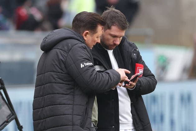2. Bundesliga - Hannover 96 - Dynamo Dresden am 22.02.2026 in der Heinz von Heiden Arena in Hannover Trainer Christian Titz (Hannover) und Pressesprecher Christoph Heckmann (Hannover) schauen sich direkt nach dem Schlusspfiff Szenen auf einem Smartphone an
