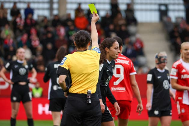 München, Deutschland 22. Februar 2026: 1. Frauen-Bundesliga - 2025 2026 - 19. Spieltag - FC Bayern München Frauen vs. VfL Wolfsburg Frauen Im Bild: v.li. die Zweite Kessya Bussy (VfL) sieht durch Schiedsrichterin Riem Hussein (Deutschland) die gelbe Karte Copyright: HMBxMedia MadeleinexFantini