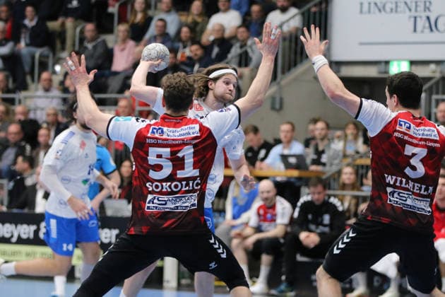 25.02.2026 Handball Herren 2025 2026 2. Handball-Bundesliga 21. Spieltag HSG Nordhorn-Lingen - Dessau-Roßlauer HV 06 EmslandArena Lingen Mika Schüler (Dessau, 23, weiß) beim Wurf. Luka Sokolic (Nordhorn, 51, rot) und Christian Wilhelm (Nordhorn, 3, rot) versuchen den Block. Lingen (Ems) Niedersachen Deutschland