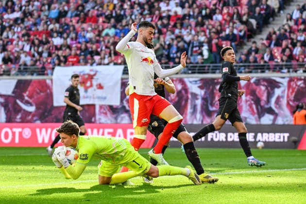 Fußball I Herren I Saison 2025-2026 I Bundesliga I 25. Spieltag I RB Leipzig - FC Augsburg I 07.03.2026 Zweikampf Finn Dahmen (1, FC Augsburg) sichert den Ball vor Romulo Cardoso (40, RB Leipzig), der über ihn springen muss Leipzig Red Bull Arena Sachsen Deutschland