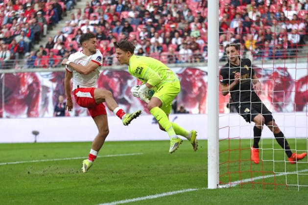1. Fußball Bundesliga: RB Leipzig - FC Augsburg; 07.03.2026 Christoph Baumgartner (14, RB Leipzig) springt mit dem Fuß voran in Torwart Finn Dahmen (1, FC Augsburg) hinein. LEIPZIG, DEUTSCHLAND - MARCH 7: Bundesliga-Spiel RB Leipzig - FC Augsburg in der Red Bull Arena am 25. Spieltag der 1. Bundesliga am March 7, 2026 in Leipzig, Deutschland. DFL REGULATIONS PROHIBIT ANY USE OF PHOTOGRAPHS AS IMAGE SEQUENCES AND OR QUASI-VIDEO.